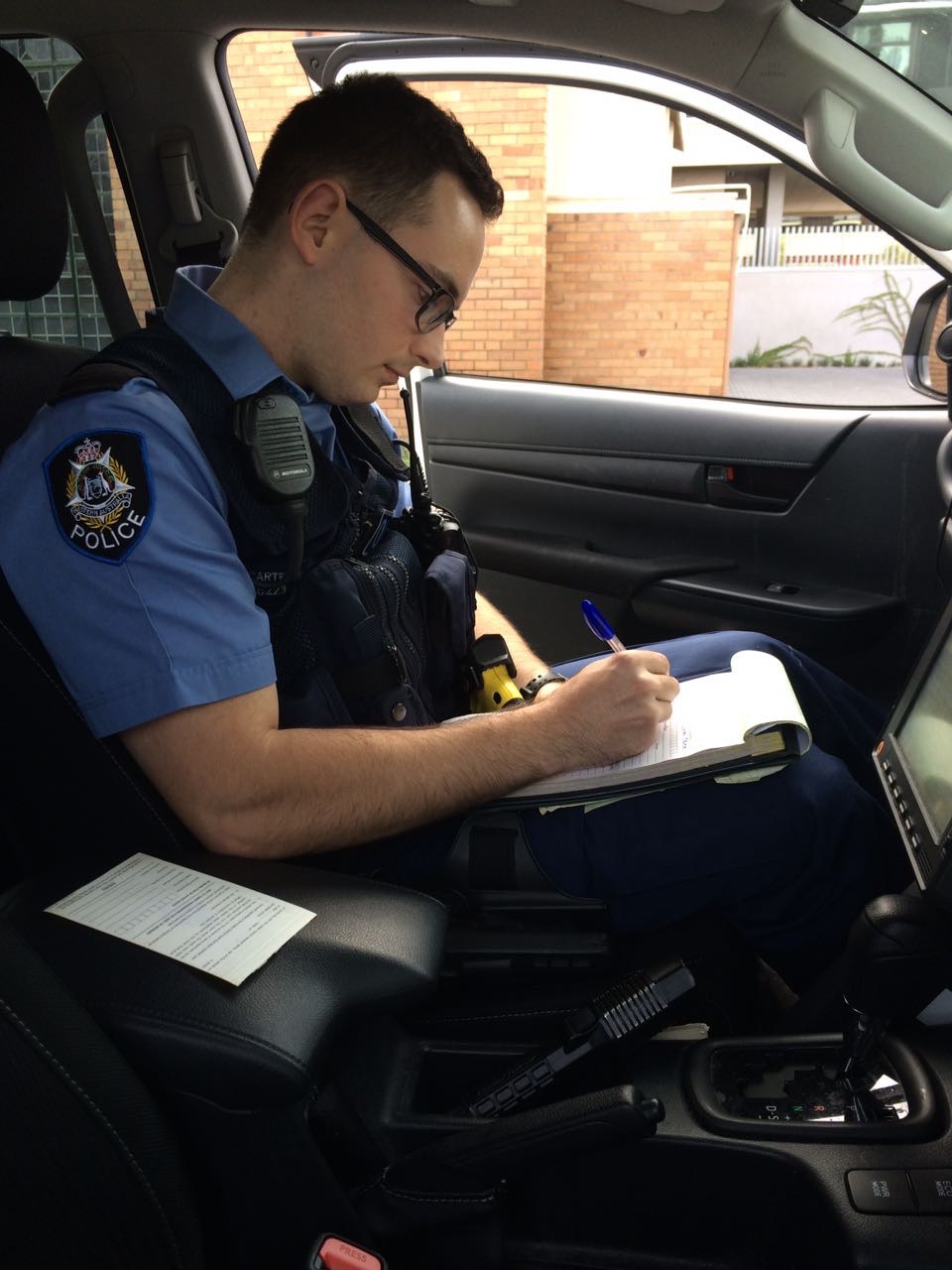 Aaron Carter writing police notes in a patrol car